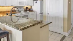 A kitchen with white cabinets, a granite countertop, and a built-in oven. - Gulf Front Condo in PCB, FL.
2 bedroom 2 bath with one set of bunks (Panama City Beach)