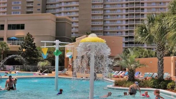 A hotel pool area with a water feature, lounge chairs, and a tall building in the background. - Gulf Front Condo in PCB, FL.
2 bedroom 2 bath with one set of bunks (Panama City Beach)