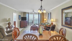 A hotel room with a dining area, a sofa, a TV, and a balcony with a view. - Gulf Front Condo in PCB, FL.
2 bedroom 2 bath with one set of bunks (Panama City Beach)