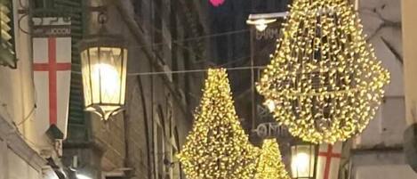 A crowded street with people walking, buildings on either side, and decorative lights.