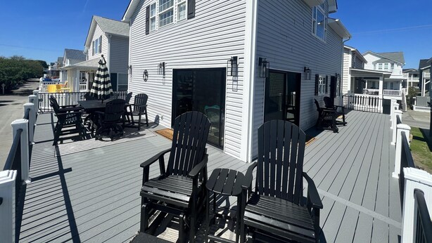 Une maison blanche dotée d’une terrasse, comprenant un espace extérieur aménagé et une zone couverte.