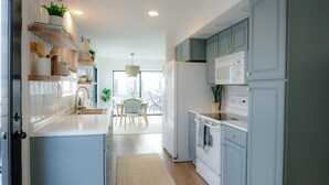 Une cuisine moderne avec des meubles de couleur bleu clair, un réfrigérateur blanc et un coin repas comprenant une table et des chaises.