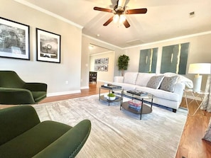 A living room with a sofa, two armchairs, a coffee table, and a ceiling fan.