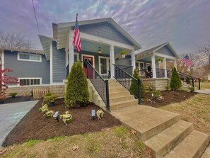 A two-story house with a front porch, a flag, and a well-maintained lawn.