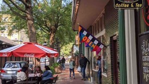 A street with outdoor seating, a building with a sign reading 'Coffee & Tea,' and a Coca-Cola branded umbrella. - *New* Beautiful 2 Bedroom in Downtown Paducah (Paducah)