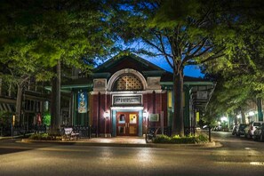A building with a marquee sign, a gated entrance, and a street view with parked cars.