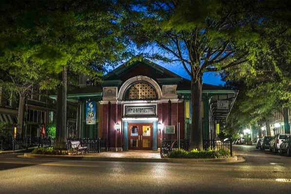 A building with a marquee sign, a gated entrance, and a street view with parked cars.