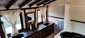 A bathroom with a large mirror, two sinks, a bathtub, and a window with curtains. - Casa campestre a 15 minutos de Salento  (Salento)