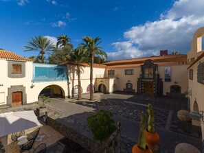 A courtyard with a tiled floor, palm trees, and a building with a tiled roof. - Cosmopolitan Design By CanariasGetaway (Las Palmas de Gran Canaria)
