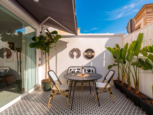 A patio with a round table and chairs, potted plants, and decorative wall art. - Cosmopolitan Design By CanariasGetaway (Las Palmas de Gran Canaria)