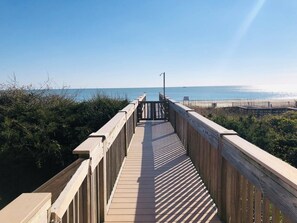 Una pasarela de madera que conduce a una playa con vista despejada al océano.