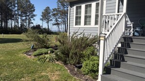A house with a porch, steps, and a garden with various plants.