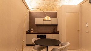 Et kompakt køkken med et rundt spisebord, to stole, en hængende lampe og en indbygget ovn.