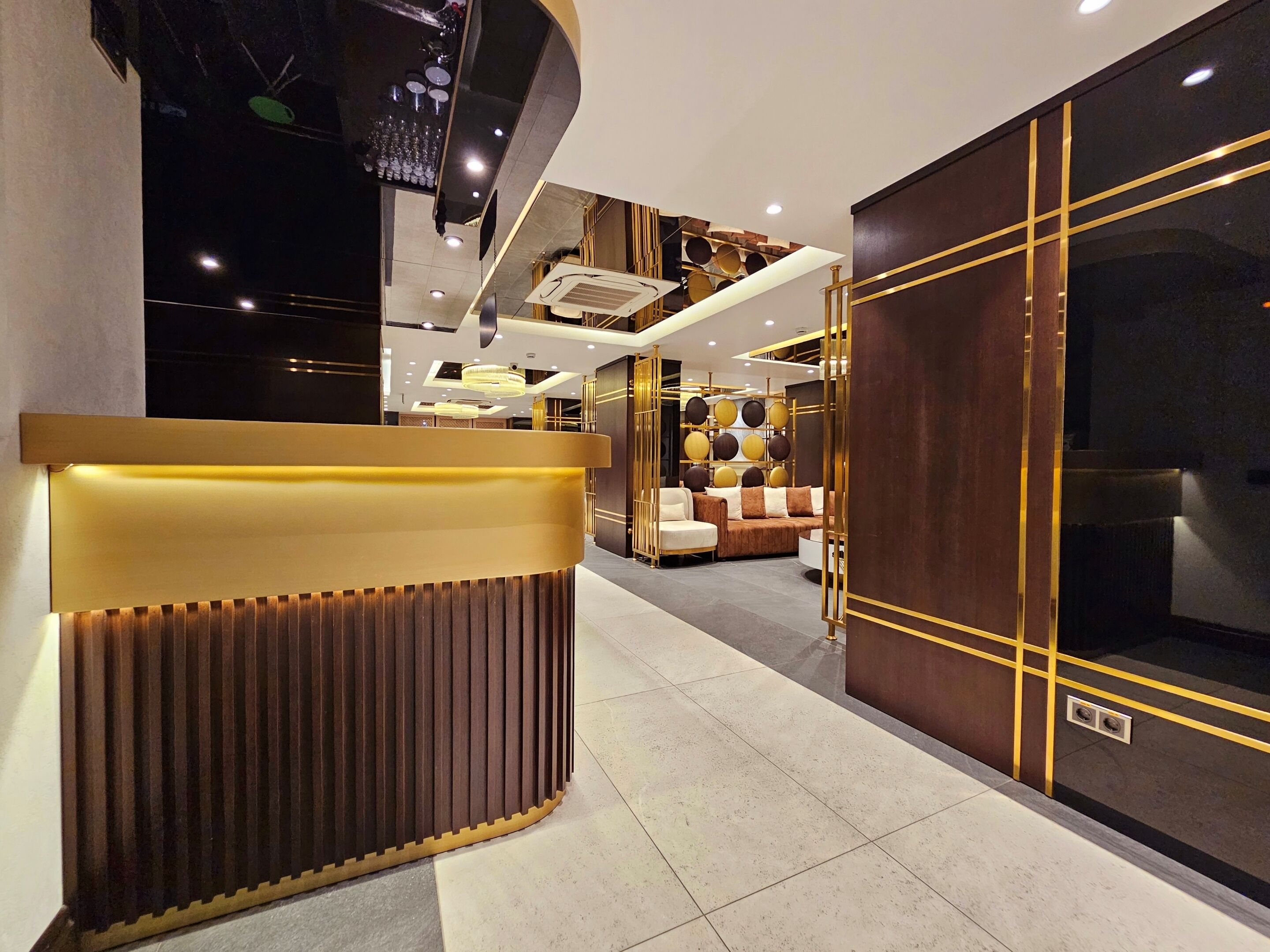 A modern hotel lobby with a reception desk, seating area, and decorative lighting.