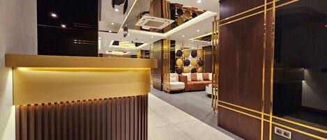 A modern hotel lobby with a reception desk, seating area, and decorative lighting.