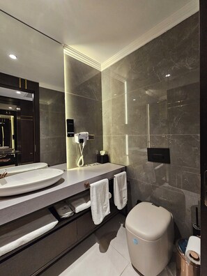 Une salle de bain moderne avec un grand miroir, deux lavabos, des toilettes et une douche.