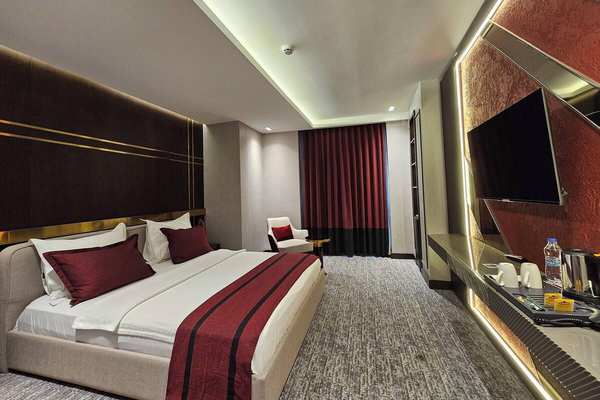 Une chambre d’hôtel avec un grand lit, une chaise, une télévision et un minibar.