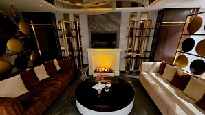 A modern living room with a fireplace, two sofas, and a round coffee table. - Asur Imperial Hotel (Midyat)