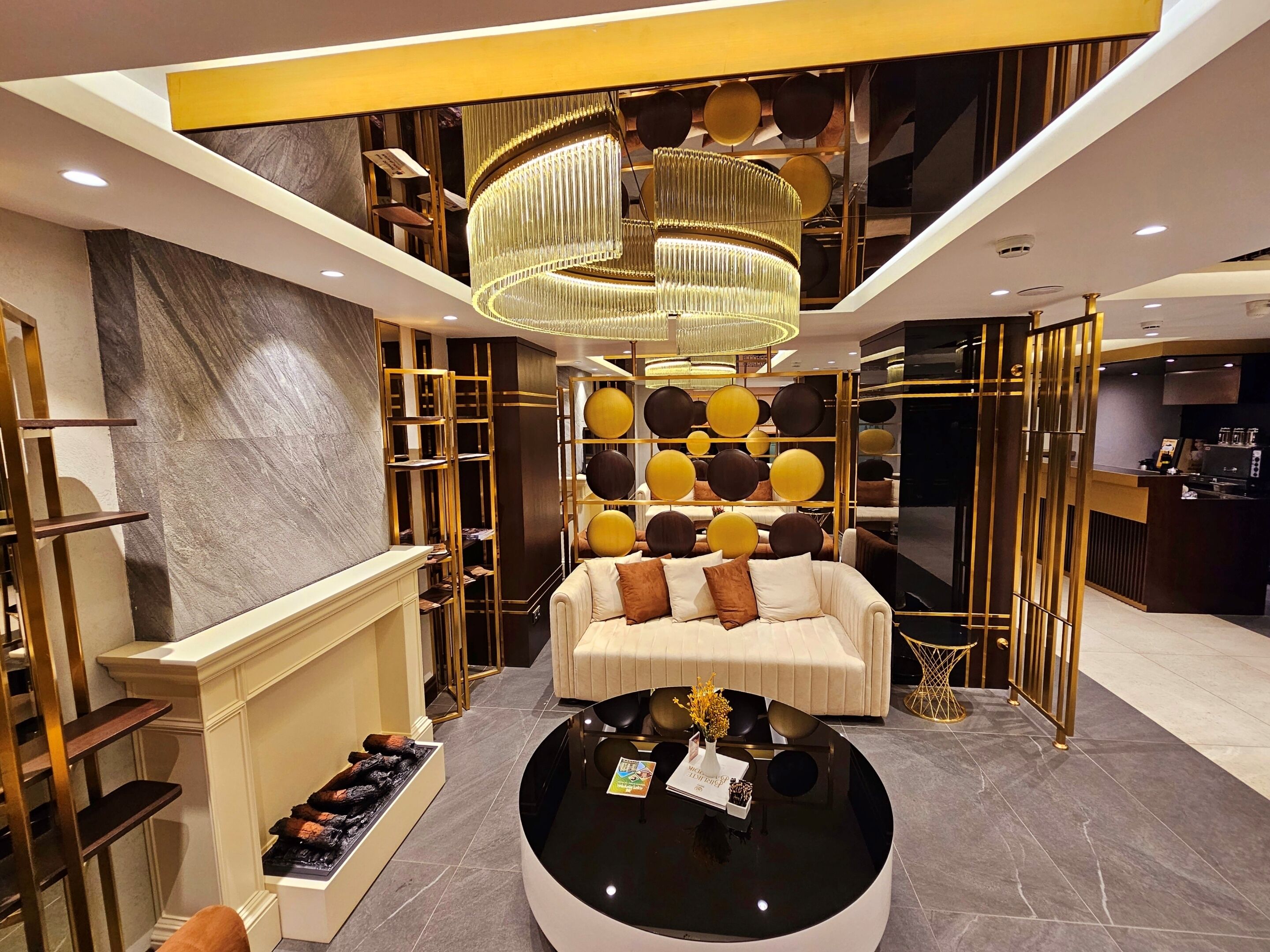 A modern lobby with a central seating area, a chandelier, and a reception desk.