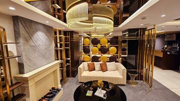 A modern lobby with a central seating area, a chandelier, and a reception desk.
