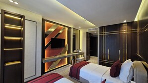 A hotel room with two beds, a TV, a vanity with a mirror, and a minibar. - Asur Imperial Hotel (Midyat)