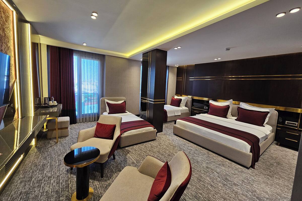 Une chambre d’hôtel avec deux lits, un canapé, une petite table et un téléviseur.