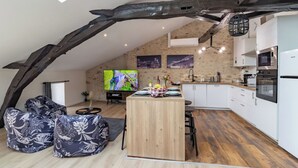 A modern loft-style kitchen with a wooden island, white cabinets, and a stone accent wall. - Le Loft - Rated 5 Stars (Mussidan)