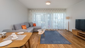 A modern living room with a sofa, coffee table, dining table set for two, and a TV. - HARAKA APARTMENT WITH SUNSET BALCONY  (Tartu)