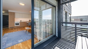 A modern apartment with a balcony, a kitchen with wooden cabinets, and a dining area with a table and chairs. - HARAKA APARTMENT WITH SUNSET BALCONY  (Tartu)