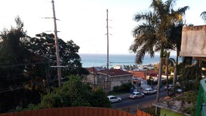 Zona residencial con vista al océano, una cerca de madera y una calle con coches.