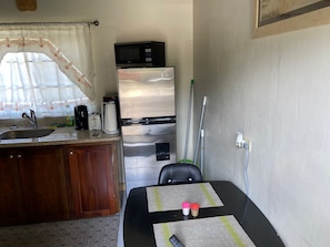 Cocina compacta con refrigerador, microondas y pileta.