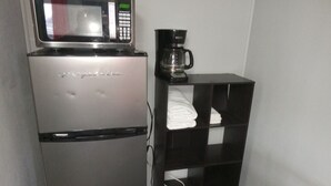 A compact kitchenette with a refrigerator, microwave, and coffee maker. - Western Hills Motel (Versailles)