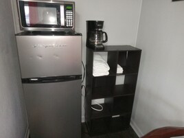 Una kitchenette compacta con refrigerador, microondas y cafetera.