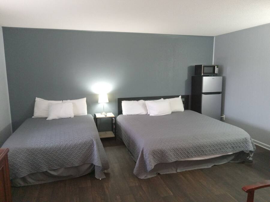 Une chambre avec deux lits, une table de chevet avec une lampe, un four à micro-ondes et un réfrigérateur.