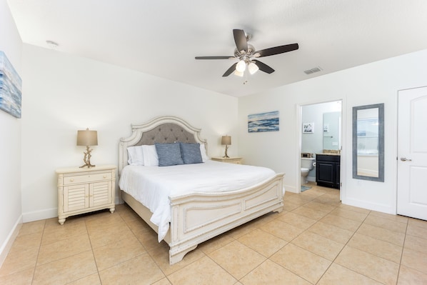 A bedroom with a bed, nightstands, a ceiling fan, and a bathroom visible through an open door.