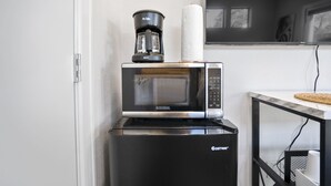 A compact kitchen with a microwave, coffee maker, and a small refrigerator.