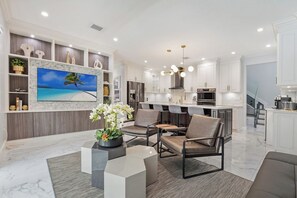 A modern kitchen with white cabinets, a built-in oven, and a dining area with chairs.