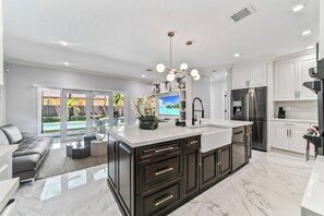 A modern kitchen with dark cabinetry, a white countertop, and stainless steel appliances.