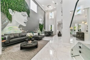 A modern living room with a grey sofa, a coffee table, and a mural on the wall.
