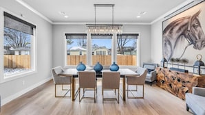 A dining area with a table, chairs, and a chandelier. - Lux 5BD Stonefront Tulsa | Near Gathering Place (Tulsa)