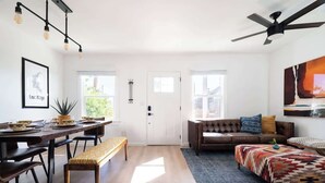 A spacious living area with a dining table, bench, sofa, and ottoman.