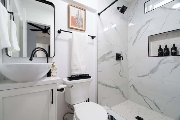 Un baño moderno con un lavabo blanco, grifo negro y un cuadro en la pared.