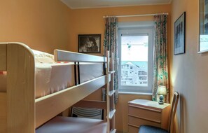 Habitación con literas, un escritorio y una silla, con ventana.