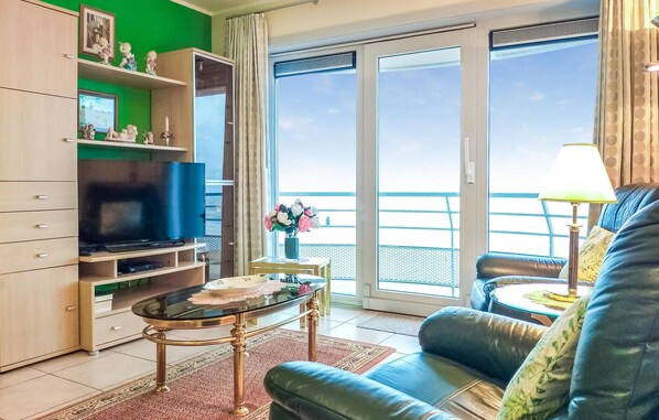 Una sala de estar con televisor, sofá, mesa de centro y balcón con vistas.