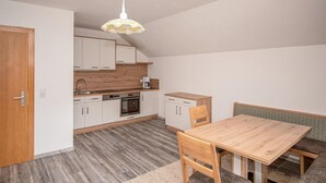 Una cocina compacta con armarios blancos, una encimera de madera y un comedor con mesa y sillas de madera.