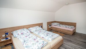 Una habitación pequeña y bien iluminada con dos camas de madera, cada una con una colcha estampada de flores y una mesita de noche con lámpara.
