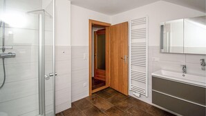 Un baño con ducha, inodoro, lavamanos y espejo.
