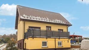 A two-story yellow building with a tiled roof and a balcony on the upper floor. - Beautiful apartment in Moryn with WiFi (Moryn)