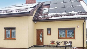 A house with a sloped roof, solar panels, a wooden door, and a small patio with chairs and a table. - Beautiful apartment in Moryn with WiFi (Moryn)