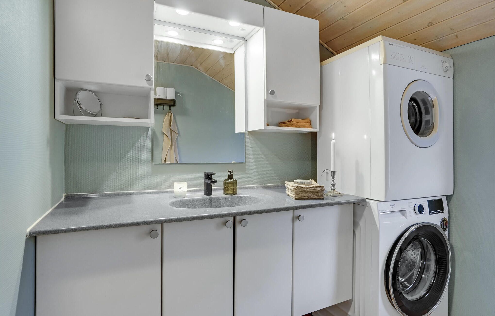 A modern bathroom with a built-in washing machine, a sink, and a mirror.